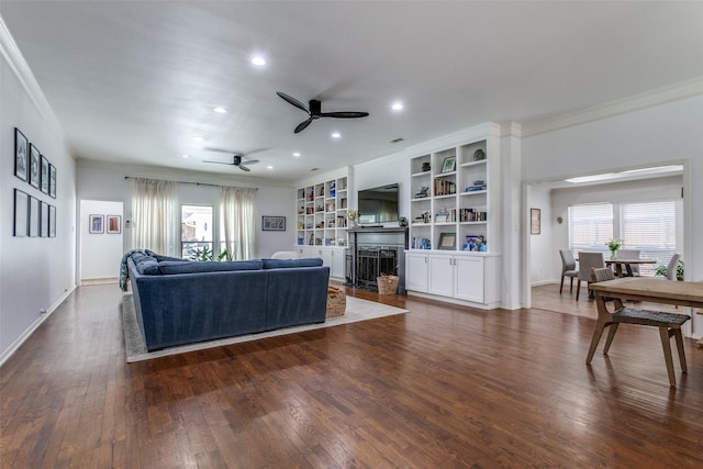 living area with a healthy amount of sunlight, dark wood-style floors, and a ceiling fan