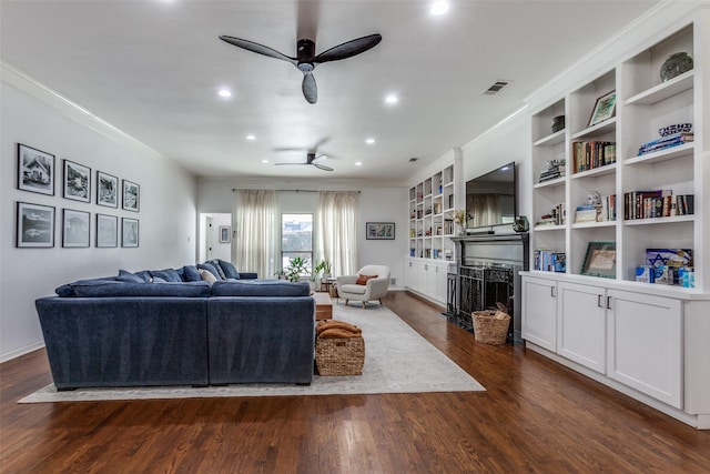 living room featuring a ceiling fan, a fireplace, dark wood-style flooring, and ornamental molding