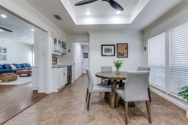 dining space with visible vents, ceiling fan, wine cooler, crown molding, and a raised ceiling