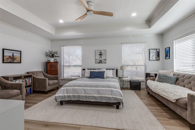 bedroom featuring a tray ceiling, multiple windows, and wood finished floors