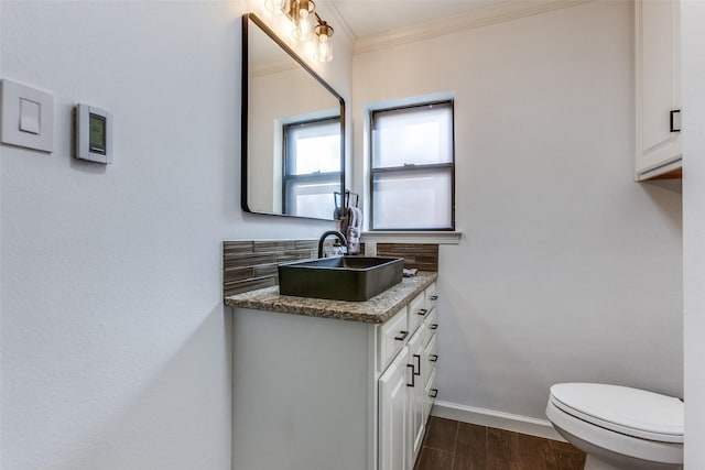 bathroom with vanity, wood finished floors, baseboards, ornamental molding, and toilet