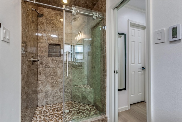 bathroom featuring a shower stall, crown molding, and wood finished floors