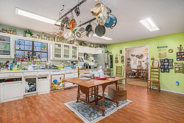 kitchen featuring light wood-style flooring, a textured ceiling, white cabinetry, stainless steel fridge, and dishwasher