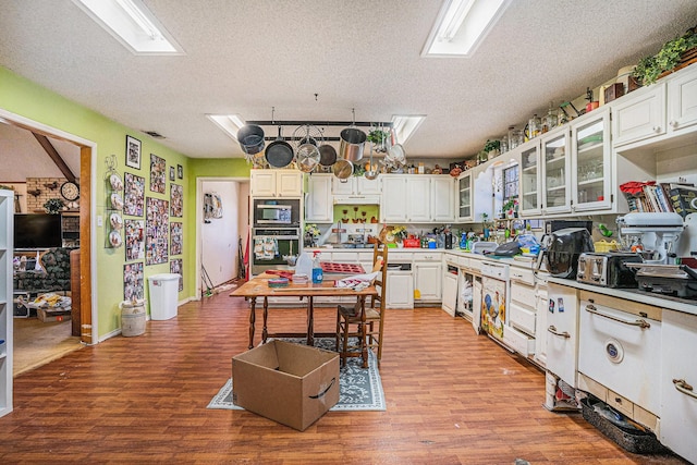 kitchen featuring light wood-style flooring, white cabinets, stainless steel appliances, and glass insert cabinets