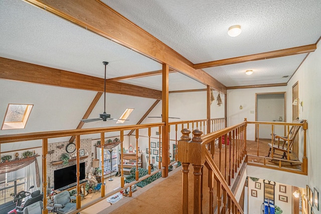 hall with lofted ceiling with skylight, an upstairs landing, a textured ceiling, and carpet