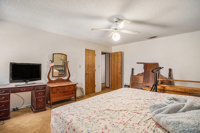 bedroom with visible vents, light colored carpet, ceiling fan, and a textured ceiling