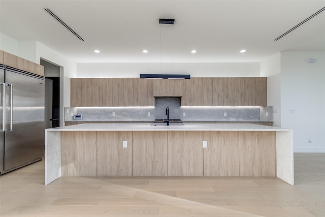 kitchen featuring modern cabinets, stainless steel built in refrigerator, light brown cabinetry, a sink, and light countertops