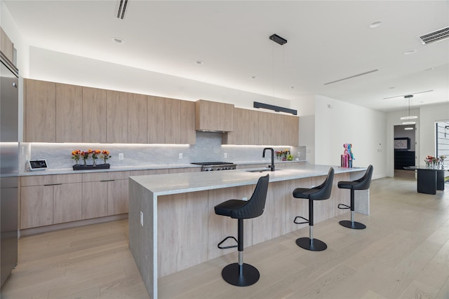 kitchen with a sink, modern cabinets, visible vents, and light brown cabinetry