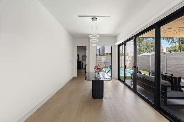 hallway featuring light wood finished floors, a healthy amount of sunlight, and baseboards