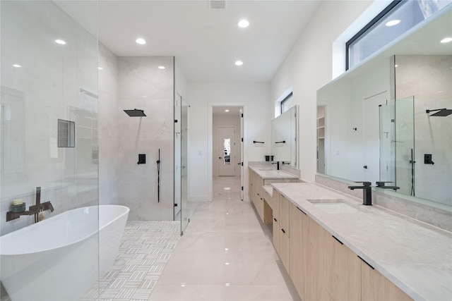 full bathroom featuring a shower stall, two vanities, recessed lighting, a freestanding tub, and a sink