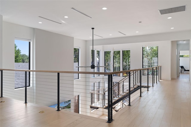 hallway with recessed lighting, visible vents, an upstairs landing, and light wood-style flooring