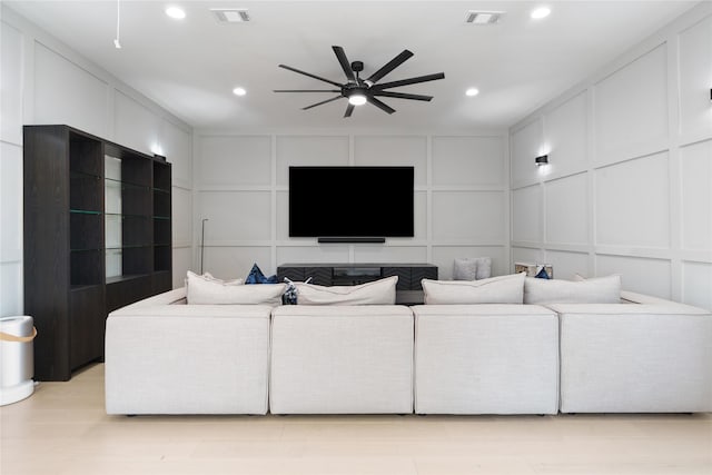 living area featuring a decorative wall, visible vents, and ceiling fan