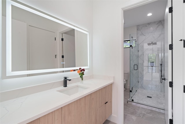 bathroom featuring a marble finish shower, recessed lighting, toilet, and vanity