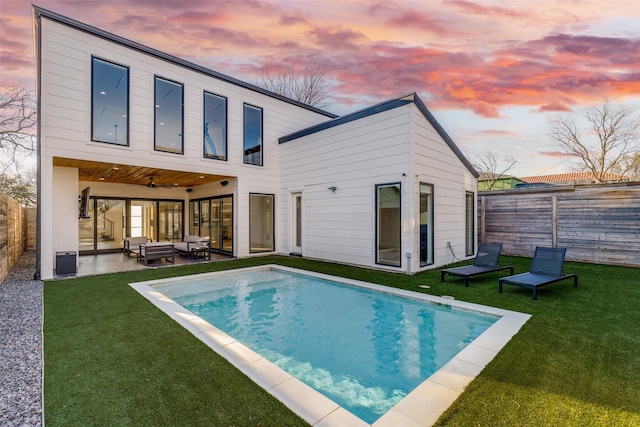 rear view of house featuring a patio, a fenced backyard, ceiling fan, outdoor lounge area, and a lawn