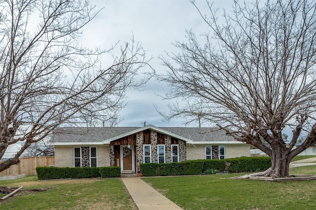 view of front of house featuring stone siding, brick siding, a front yard, and fence