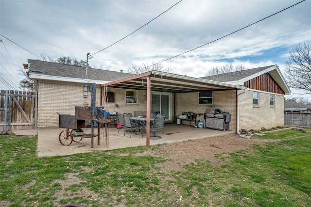 back of property featuring a lawn, a gate, fence, brick siding, and a patio area