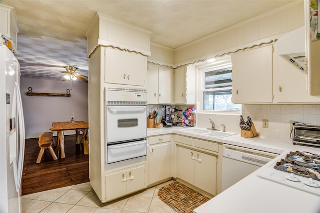 kitchen featuring a warming drawer, a sink, white appliances, light countertops, and light tile patterned floors