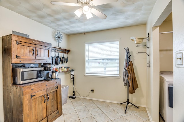 kitchen featuring a ceiling fan, baseboards, washer / dryer, stainless steel microwave, and brown cabinets