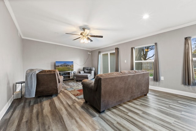 living room featuring baseboards, wood finished floors, a ceiling fan, and ornamental molding