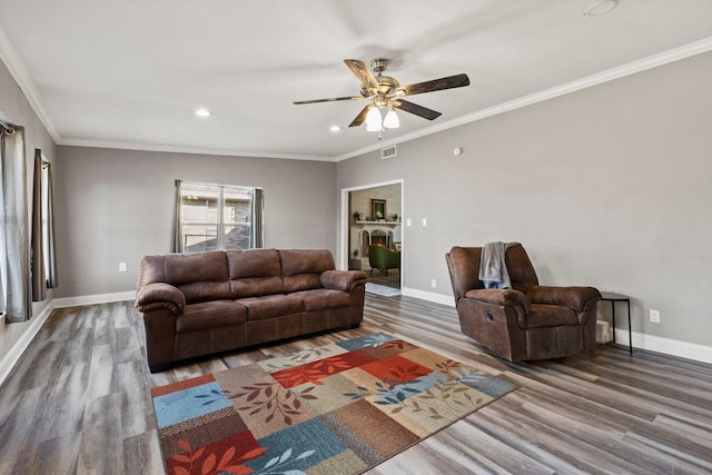 living area featuring wood finished floors, baseboards, visible vents, and ornamental molding