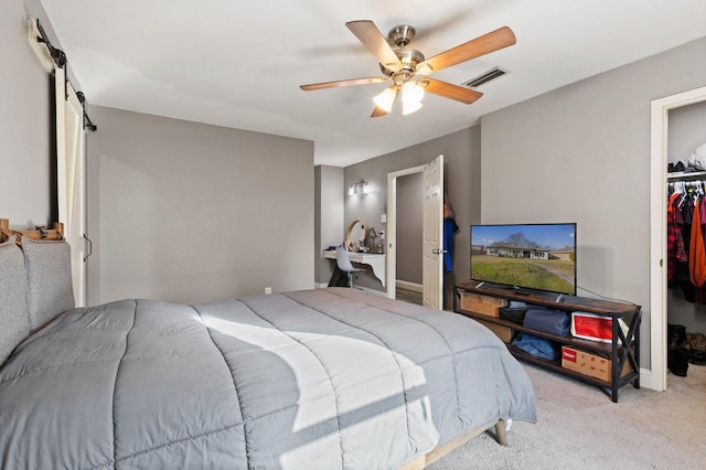 bedroom featuring a spacious closet, visible vents, a barn door, carpet floors, and a closet