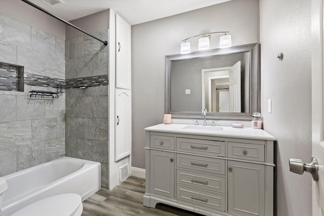 bathroom featuring visible vents, toilet, wood finished floors,  shower combination, and vanity