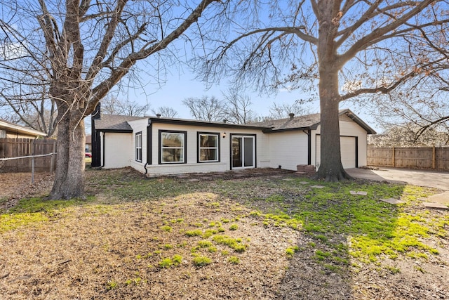 mid-century home with brick siding, driveway, a garage, and fence