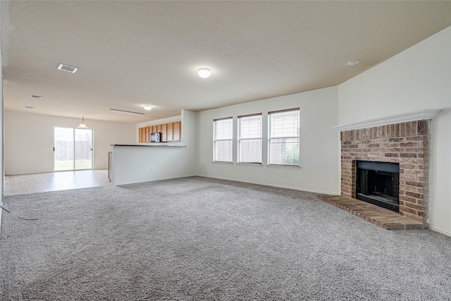 unfurnished living room with a brick fireplace, a healthy amount of sunlight, visible vents, and light carpet