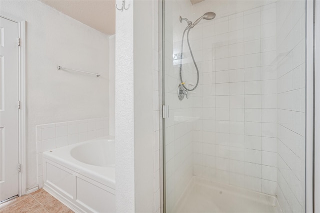 bathroom featuring tile patterned flooring, a shower stall, and a bath