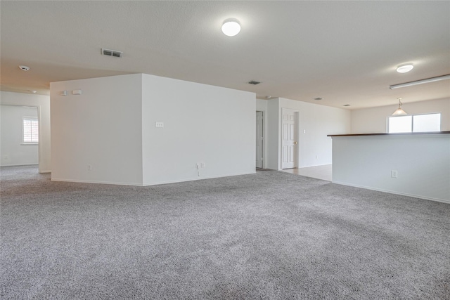 empty room featuring baseboards, visible vents, and light carpet