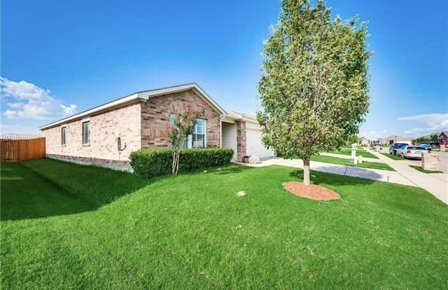 exterior space featuring fence, concrete driveway, an attached garage, a front yard, and brick siding