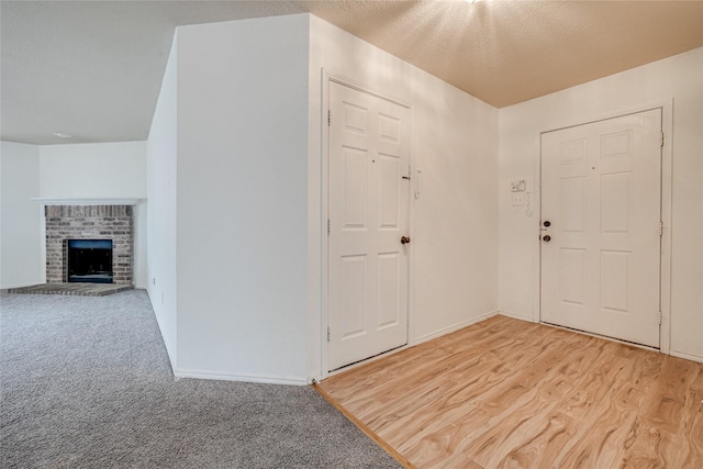 carpeted foyer featuring a fireplace, baseboards, and a textured ceiling