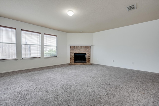 unfurnished living room featuring visible vents, a textured ceiling, carpet flooring, and a fireplace