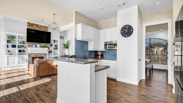 kitchen with visible vents, white cabinetry, dark wood-style floors, and stainless steel microwave