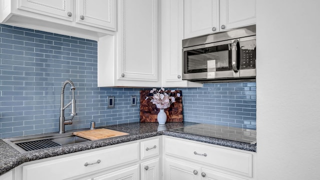 kitchen featuring a sink, stainless steel microwave, and decorative backsplash