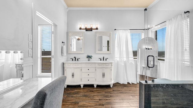 full bath featuring crown molding, wood finished floors, double vanity, and a sink