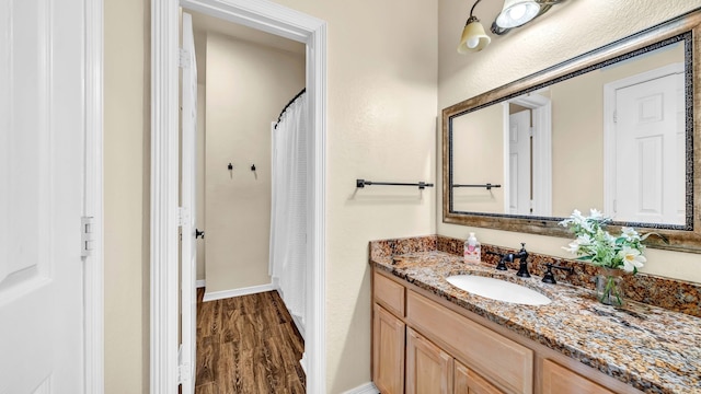 bathroom featuring vanity, wood finished floors, and baseboards