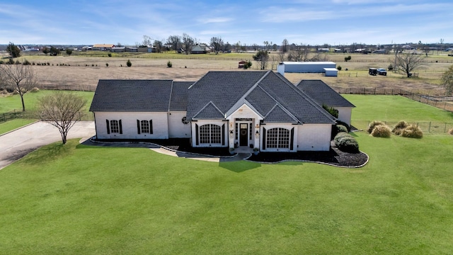 french provincial home featuring a rural view, a front lawn, and fence