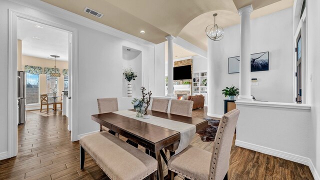 dining space with wood finished floors, visible vents, ornate columns, and baseboards