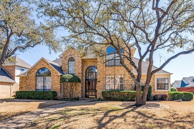 view of front of house featuring brick siding, a front yard, and roof with shingles