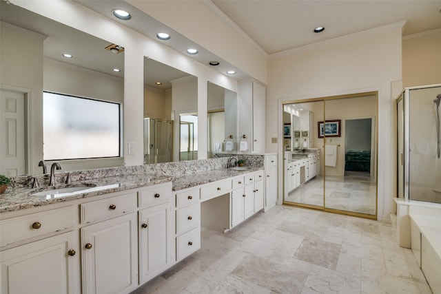 bathroom with double vanity, a stall shower, crown molding, and a sink