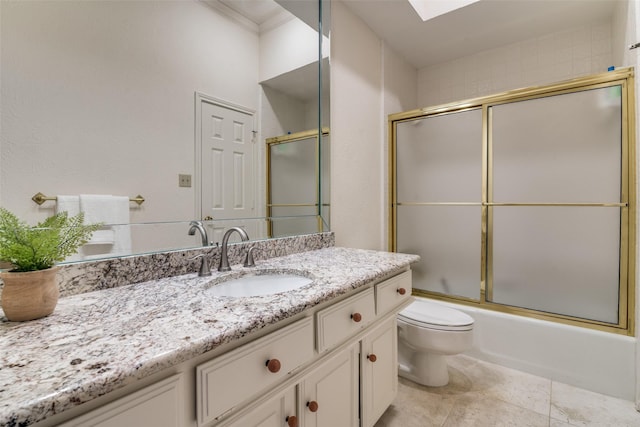 bathroom featuring toilet, a skylight, vanity, and shower / bath combination with glass door