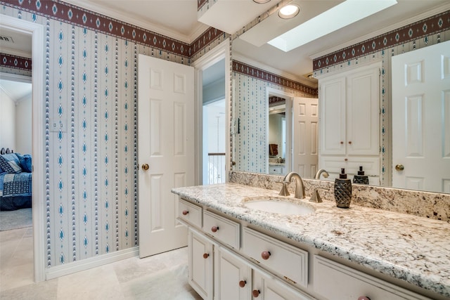 bathroom with wallpapered walls, crown molding, a skylight, and vanity