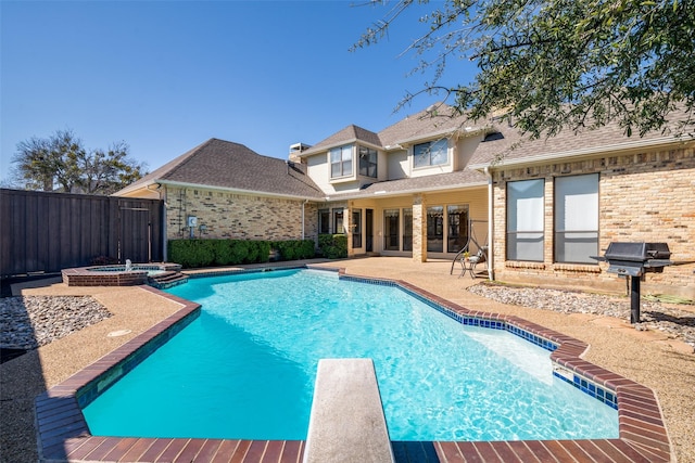 view of pool featuring a pool with connected hot tub, fence, grilling area, a diving board, and a patio area