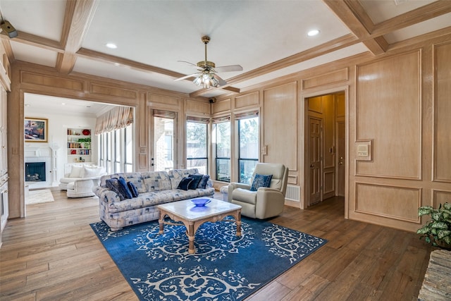 living area featuring beamed ceiling, coffered ceiling, a fireplace, and hardwood / wood-style floors