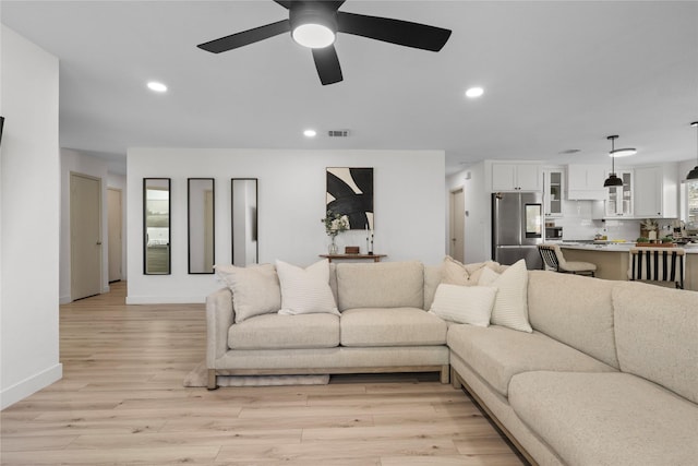 living area featuring visible vents, a ceiling fan, recessed lighting, light wood finished floors, and baseboards