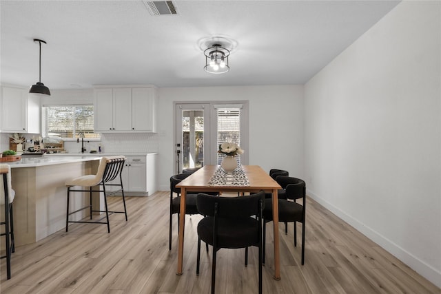 dining area with light wood-style floors, a healthy amount of sunlight, visible vents, and baseboards
