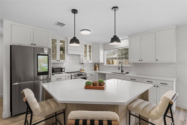 kitchen with a sink, visible vents, a kitchen bar, and stainless steel appliances