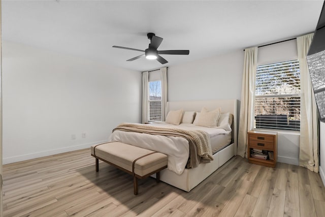 bedroom with light wood-style floors, baseboards, and ceiling fan