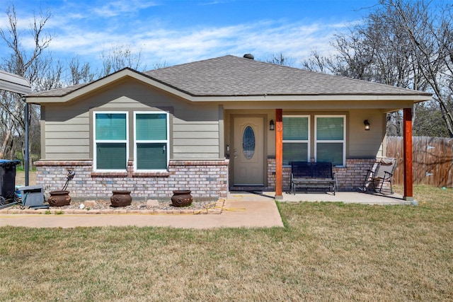 bungalow-style home featuring brick siding, roof with shingles, a front lawn, and fence